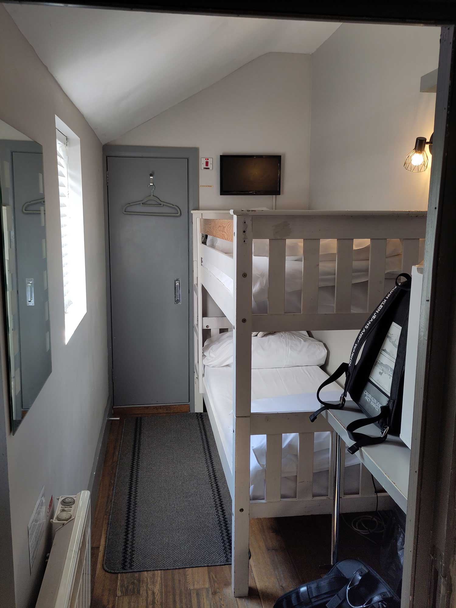 A tiny hotel room with a bunk bed.
