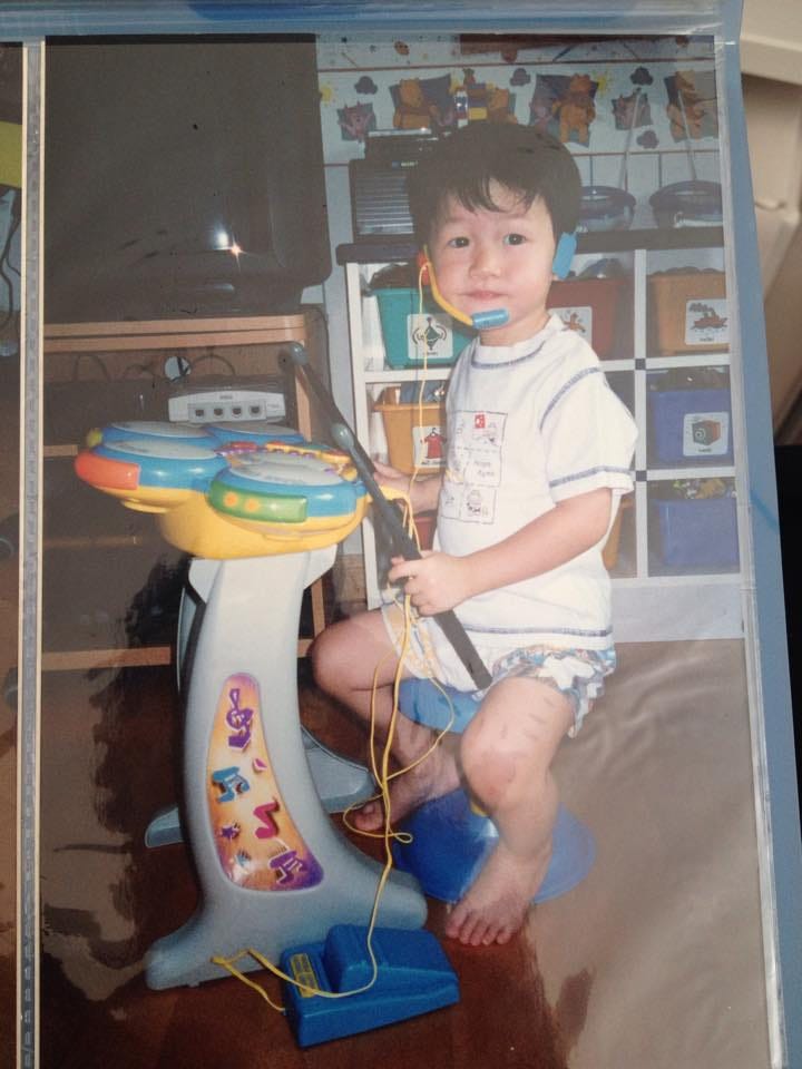 A young Doug sat behind a kid electronic drum set.